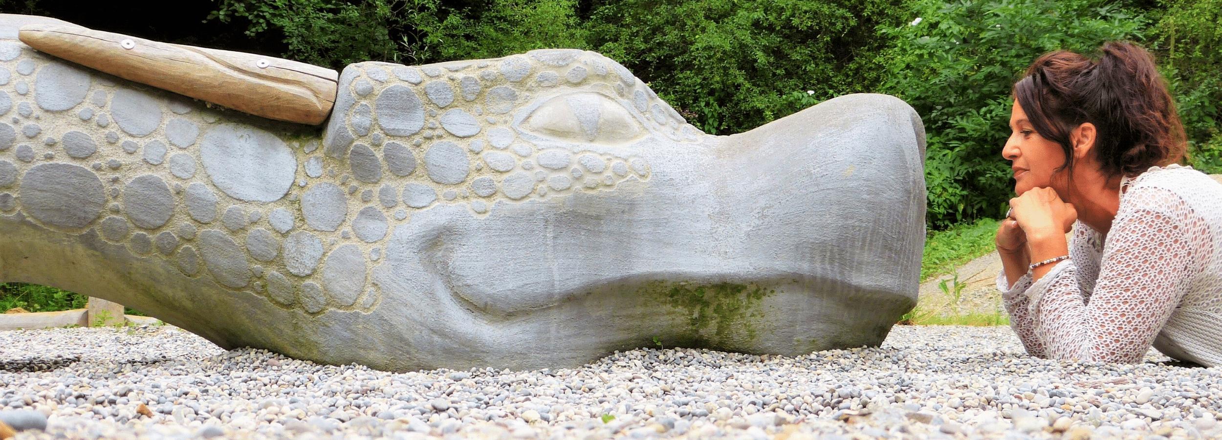 Woman smiling at a friendly dragon sculpture